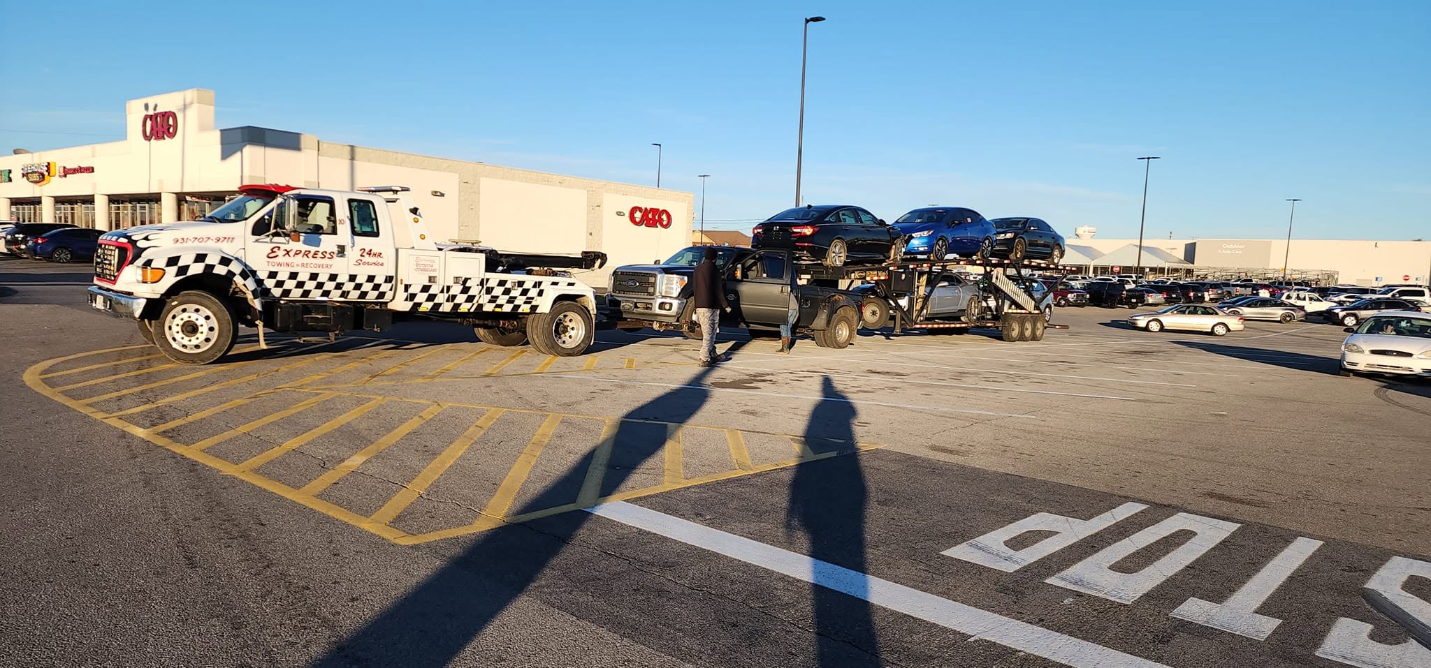 Express Towing and Recovery truck beside a vehicle transporter