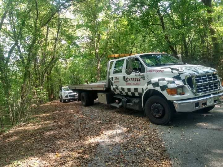 Express Towing and Recovery flatbed truck on a wooded road
