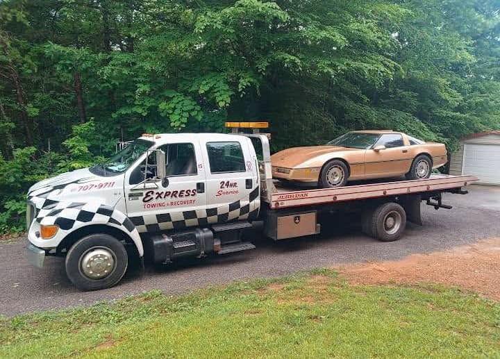 Express Towing and Recovery flatbed tow truck transporting a car