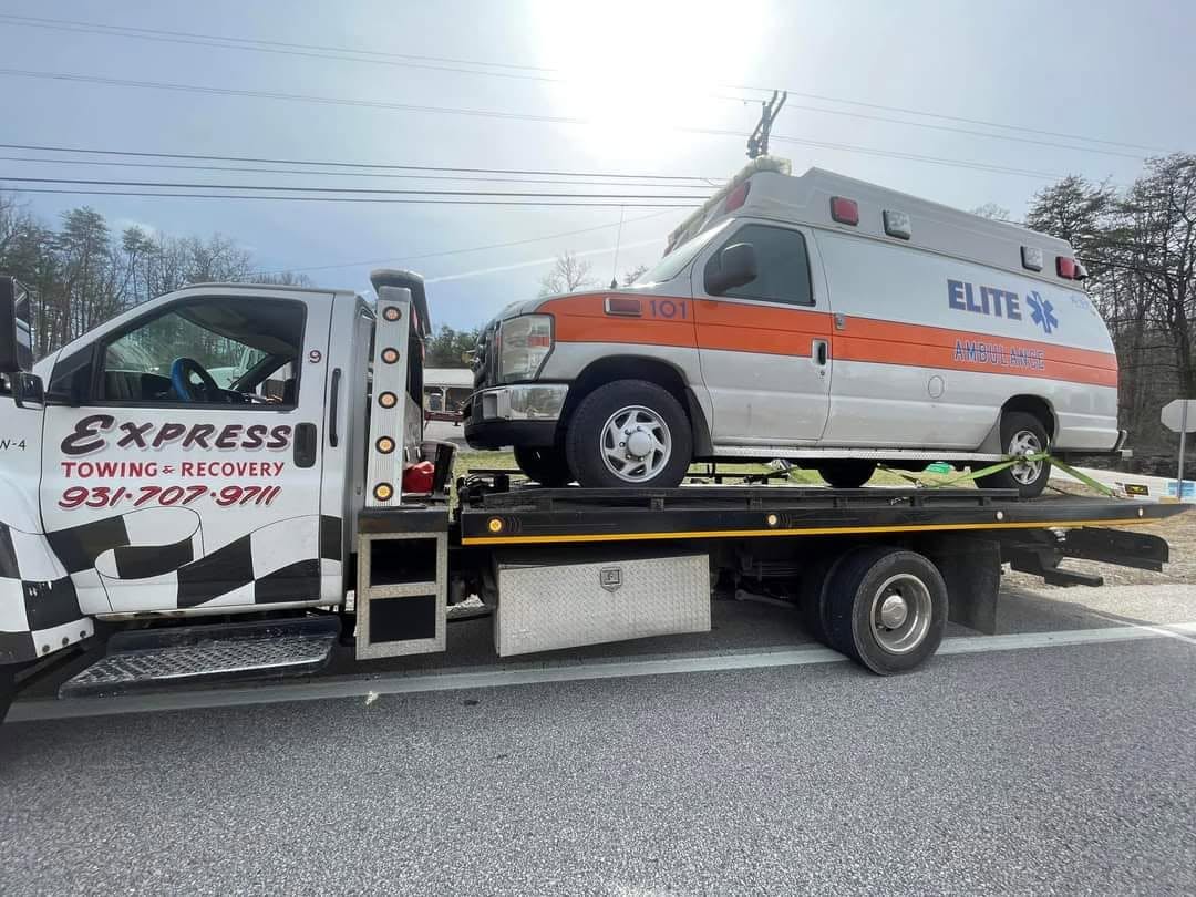 Express Towing and Recovery flatbed transporting an ambulance